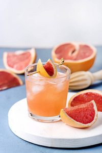 新鲜葡萄柚夏季酒精鸡尾酒葡萄柚汁冰蓝色背景垂直葡萄柚排毒