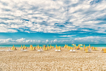 美国迈阿密多云的沙滩椅和雨伞。在晴朗的日子, 沙滩上有白沙和蓝色的海水。在海上或海洋上的暑假。流浪或旅行和冒险