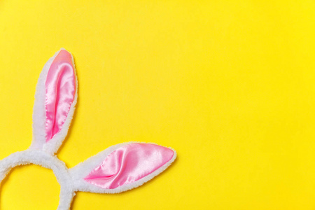 快乐复活节的概念。 为假期做准备。 装饰兔子耳朵毛茸茸的毛茸茸的服装玩具孤立在时尚的黄色背景上。 简单的极简主义，平面，俯视图，