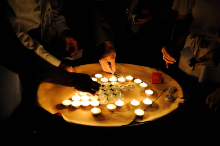 人们点燃站在托盘上的小蜡烛。 在黑暗中点燃蜡烛。