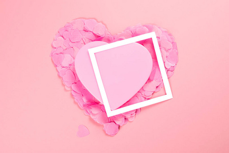优雅而温柔的粉红色心上散落的心形纸屑与白色框架。 温柔和爱的心情。 情人节的象征。