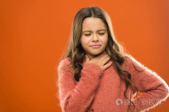 孩子感到喉咙疼.受疼痛颈部的影响.女孩痛苦的脸橙色的背景.