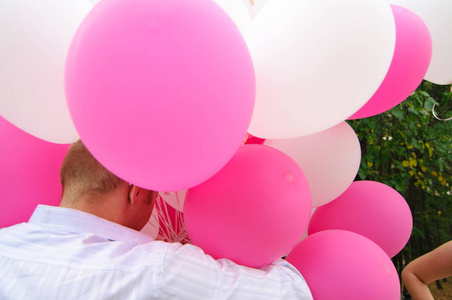 一个男人拿着一大堆白色和粉红色的气球。