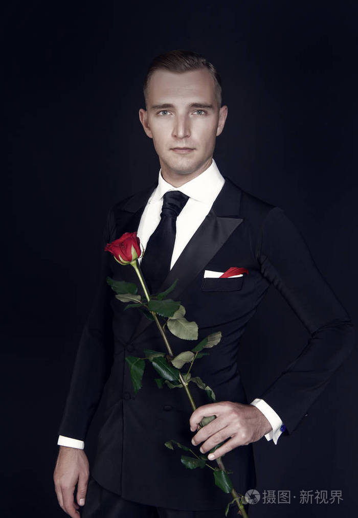 男子西装与玫瑰在黑暗的背景下