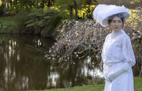 戴着白色系综和花园里的帽子的爱德华女人