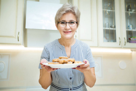 漂亮的成年女人，手里拿着饼干在厨房里