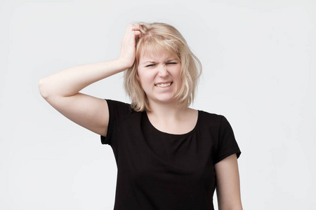 美丽的年轻金发碧眼的女人抓头照片