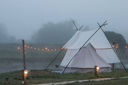 在雾蒙蒙的早晨，用山景把帐篷铺在河边。