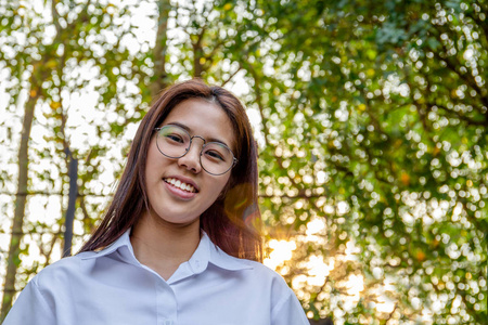 亚洲大学女子的肖像，在模糊的背景下微笑，日落