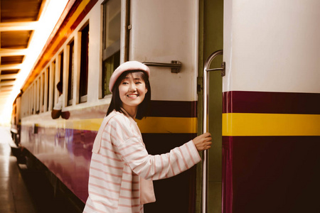 漂亮的女人正在火车站乘公共火车回家。 有魅力的漂亮女人用笑脸快乐。 魅力女孩对火车服务满意