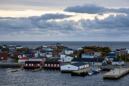 在多云的日落中，在岩石大西洋海岸的一个小镇上的家。 在加拿大纽芬兰的巴斯克港。