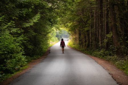 西北环线道路在一个充满活力的夏日,女人走在风景优美的森林道路上.