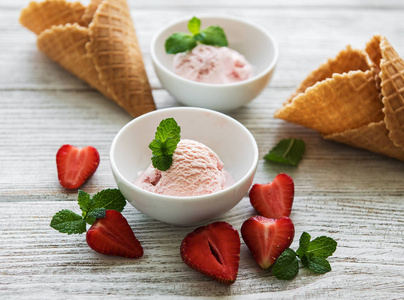 木制背景的草莓冰淇淋和华夫饼锥