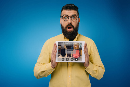 令人震惊的长胡子男子呈现数字平板电脑与在线预订应用程序隔离蓝色