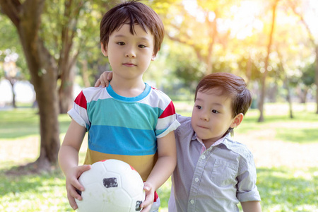 英俊的哥哥拿着球，准备和弟弟一起在公园里玩。 小男孩总是和他的大哥哥在一起，他们总是在一起玩。 他们彼此相爱