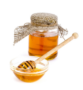 玻璃罐与美味的新鲜蜂蜜隔离在白色背景。 摄影工作室