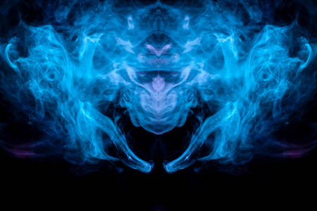 彩色烟雾背光蓝色和绿松石的抽象图案采用神秘生物的头部的形式，翅膀在黑色的孤立背景上。 灵魂和内心的思想状态