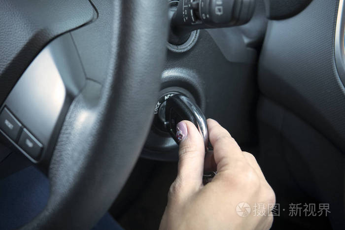 关闭女性手,转动钥匙开始自动. 带粉色指甲的女孩驾驶汽车