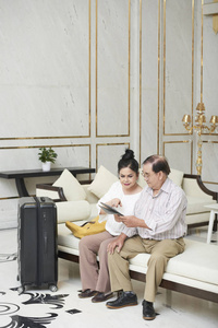 坐在酒店大厅的老夫妇在平板电脑上阅读数据
