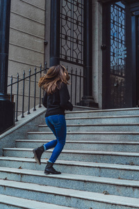 黑发女孩跑下城市的楼梯,微笑着照片