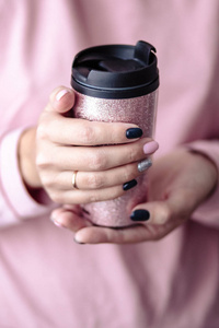 华丽的指甲膏，嫩粉红色指甲油特写照片。 女性手拿着塑料咖啡杯，背景简单