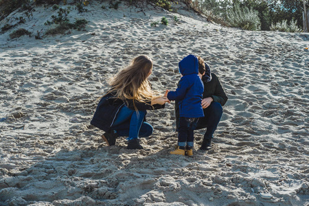 一个带着孩子的年轻家庭周末和一个小孩子一起度过寒冷的波罗的海沙滩温暖的夹克家庭周末