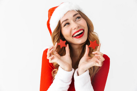 一位20多岁的黑发女子的肖像，身穿圣诞老人的红色服装，微笑着，把圣诞装饰品孤立在白色背景上