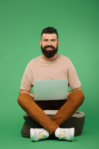 笑脸大胡子男子用笔记本电脑隔离在绿色