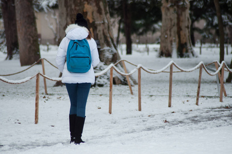 雪天穿着冬衣在城市公园散步的年轻女孩的画像