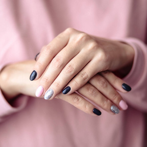 华丽的指甲膏，嫩粉红色指甲油特写照片。 女性双手简单背景