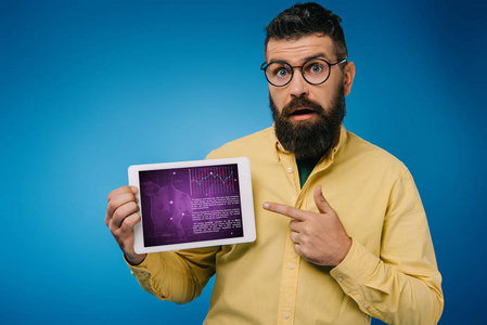震惊的胡须男子指向数字平板电脑与信息，隔离在蓝色