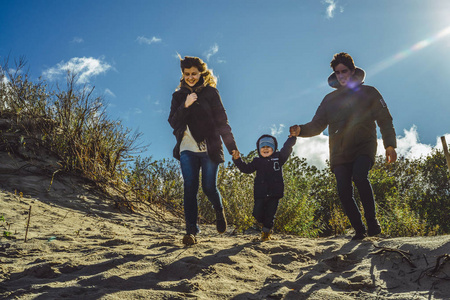 一个带孩子的年轻家庭周末在寒冷的波罗的海海岸沙滩温暖的夹克衫带孩子的家庭周末度过。