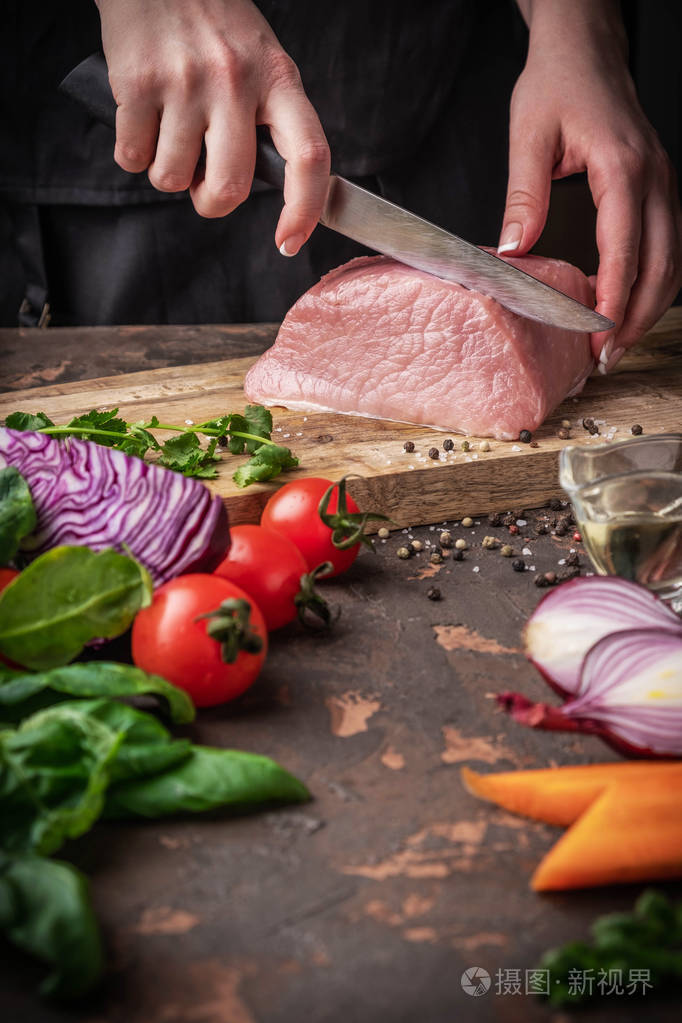 女性手在厨房的木板上切生肉用蔬菜和香料烹饪肉类的过程