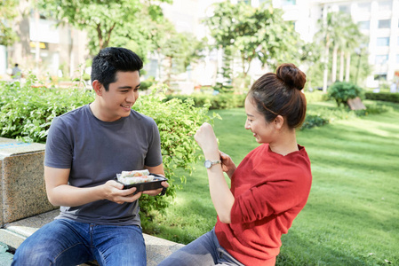 快乐的年轻越南夫妇用街头食品给她的男朋友拍照