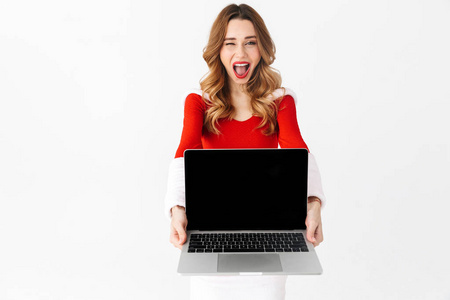 一个相当兴奋的女人穿着圣诞服装展示笔记本电脑的形象。