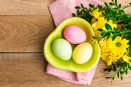 复活节3个鸡蛋放在绿色的盘子里，放在木制的背景上，一个春天的基督教节日