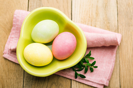 复活节3个鸡蛋放在绿色的盘子里，放在木制的背景上，一个春天的基督教节日