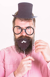 穿粉色衬衣的人拿着派对 acsessories时髦的胡子庆祝生日, 党的概念。胡子男子描绘绅士与顶帽子, 圆眼镜和黑胡子的纸