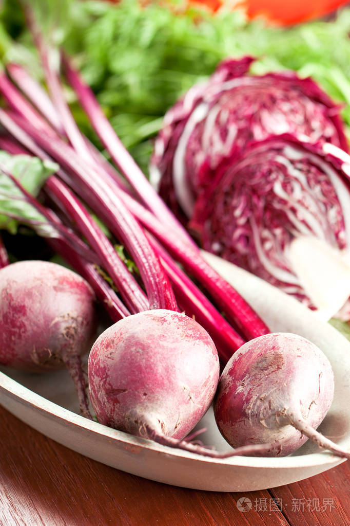 木桌上的鲜熟未加工甜菜根和紫甘蓝的近景