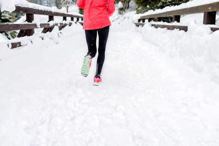 在冬天的山上，年轻的女人在雪地上奔跑，在下雪的天气里戴着温暖的衣服手套。运动，健身的灵感和动力..快乐的少女踪迹奔跑。女性跑步者