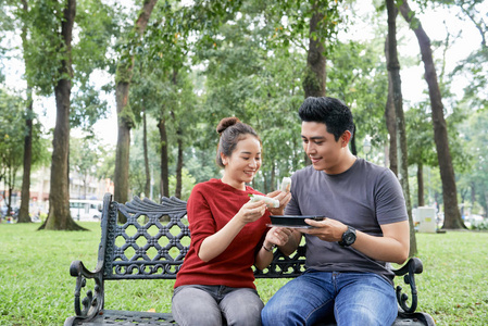 快乐的亚洲年轻夫妇在公园吃春卷
