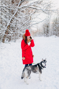冬天公园里的年轻女孩带着她的哈士奇狗。家养宠物。沙哑