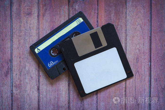 棕色木制背景的古董电脑磁盘和磁带