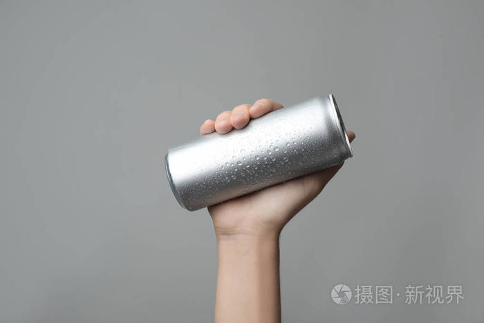妇女持有铝罐与饮料在灰色背景特写设计空间