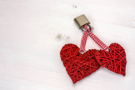 两颗红心在白色木质背景上用挂锁锁住。情人节贺卡的概念。