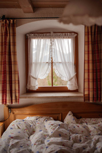 有格子窗帘和木床的窗户的房间