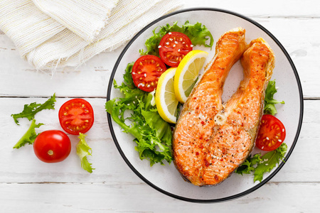 鲑鱼鱼排，烤和新鲜蔬菜沙拉与番茄和生菜。 健康的食物。 顶部视图