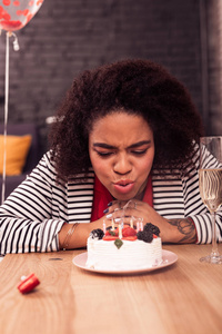 在蛋糕上吹蜡烛的漂亮快乐的女人照片