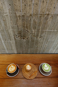 一杯绿茶抹茶拿铁和一杯木制背景的拿铁艺术咖啡