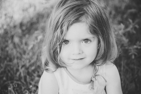 女孩棕色眼睛在可爱的面孔坐在草